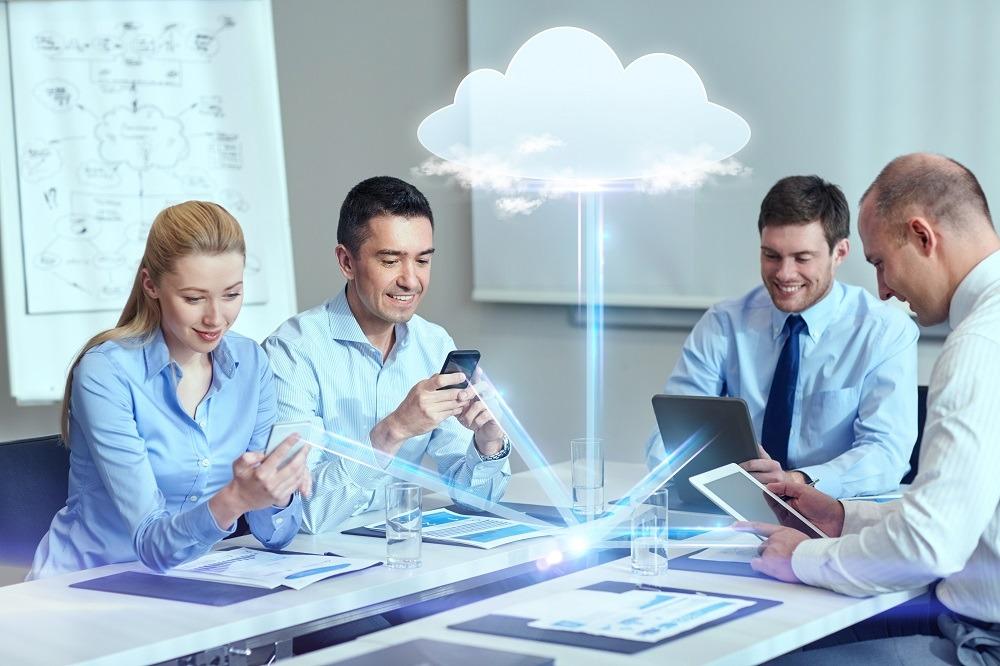group-people-cloud-technology Group of people sitting at a table with technology